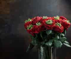 Free photo bouquet of red flowers in glass vase in dark background