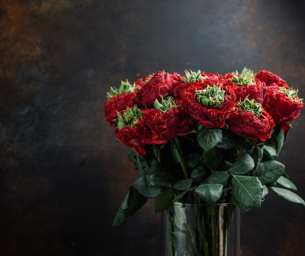 bouquet of red flowers in glass vase in dark background