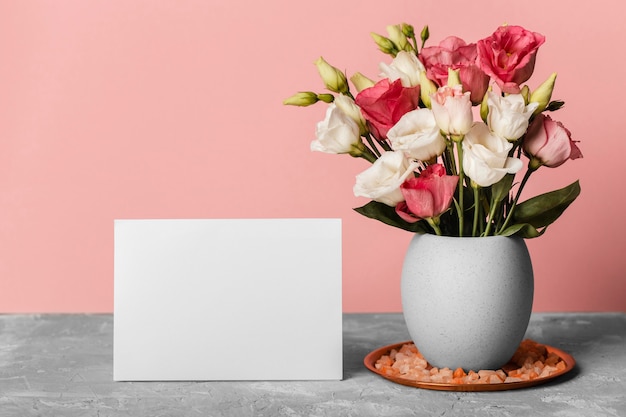 空白のカードの横にある花瓶のバラの花束