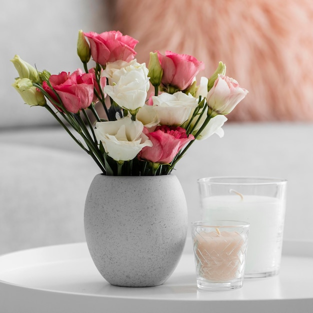 Free photo bouquet of roses in a vase next to candles