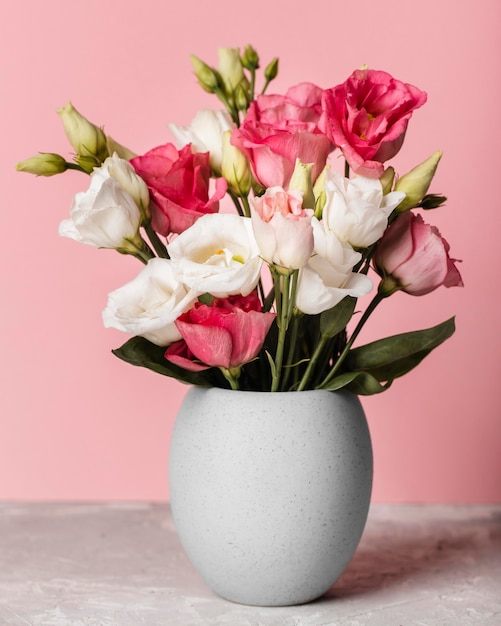 Bouquet of roses in a vase next to a pink wall