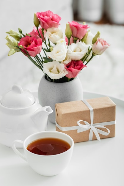 Bouquet of roses in a vase next to a wrapped gift