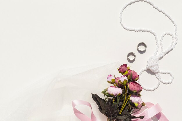 Bouquet of roses next to wedding items with copy space