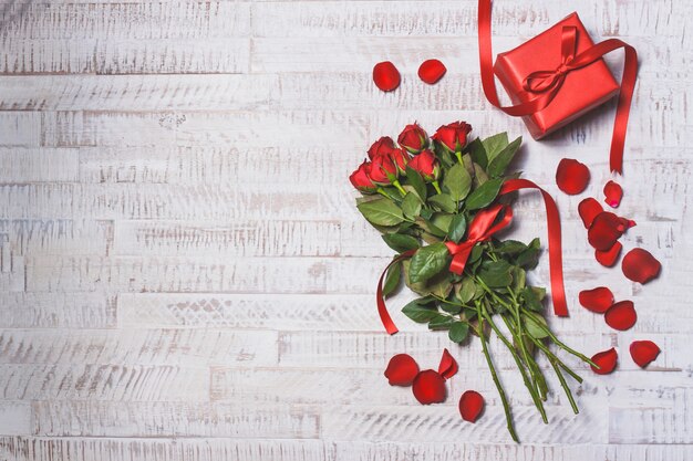 Bouquet of roses on a wooden table with a gift