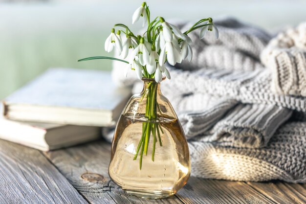 A bouquet of snowdrops in a glass vase on a blurred background