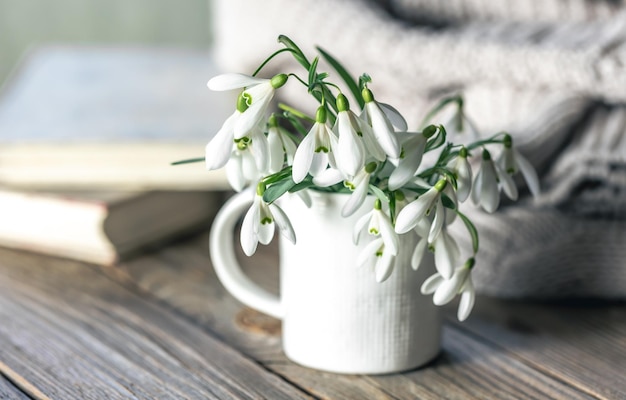 Free photo a bouquet of snowdrops in a white cup on a blurred background
