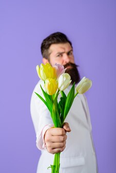 Bouquet of tulips bearded man holds bouquet of flowers handsome man with flowers businessman with