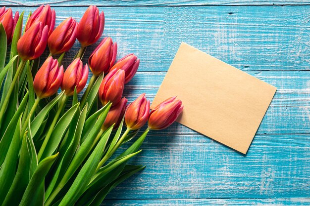 A bouquet of tulips and a piece of paper for text on a wooden background
