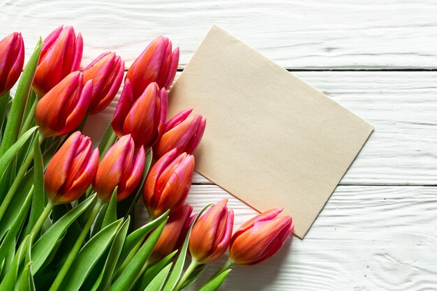 A bouquet of tulips and a piece of paper for text on a wooden background