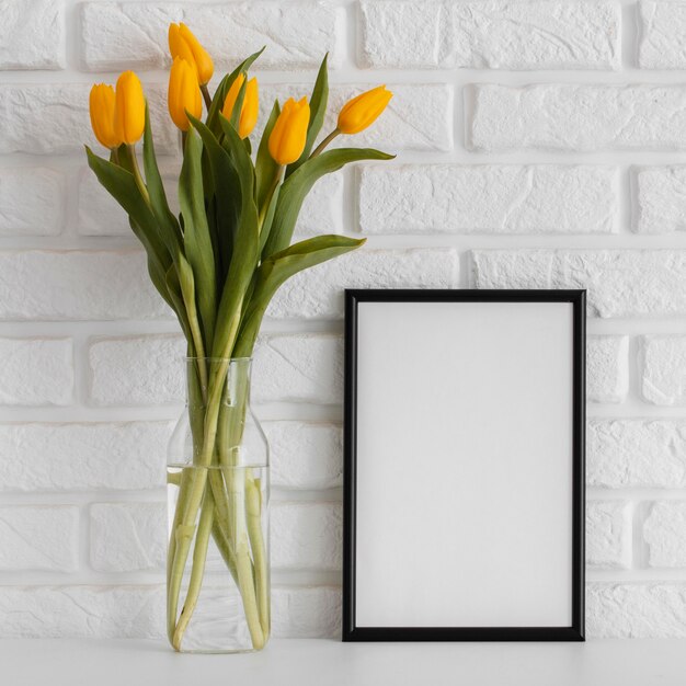 Bouquet of tulips in transparent vase with empty frame
