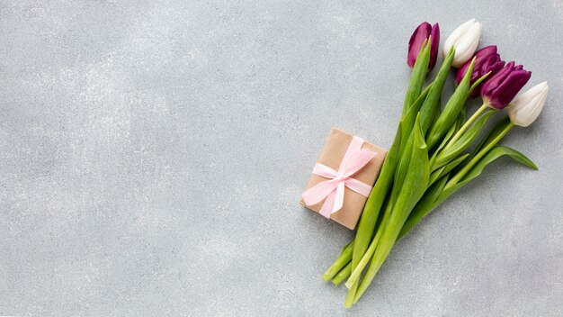 Bouquet of tulips with wrapped gift and copy space