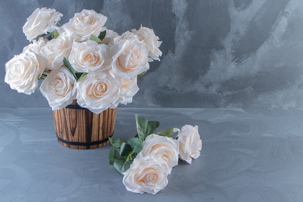 A bouquet of white flowers in a bucket, on the white table.