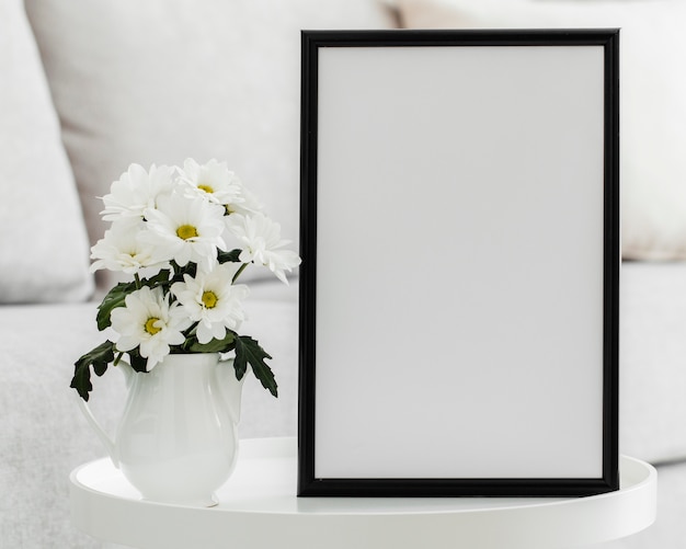 Foto gratuita bouquet di fiori bianchi in un vaso con cornice vuota