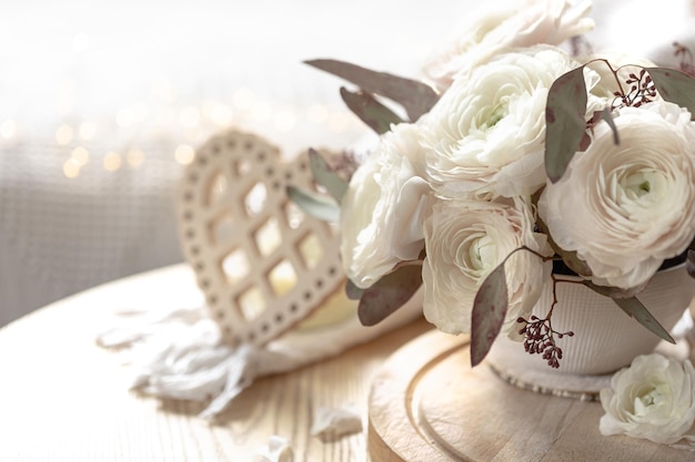 Foto gratuita bouquet di fiori bianchi di ranunculus su uno sfondo sfocato con un cuore