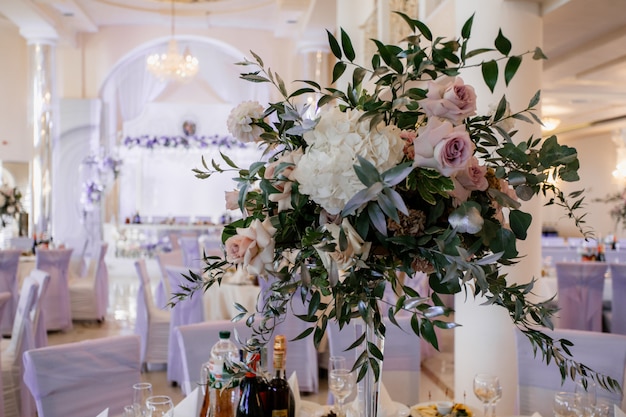 Bouquet with flowers and greenery decorated stand on the feast table