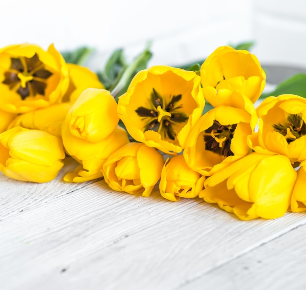 Foto gratuita bouquet di tulipani gialli su uno sfondo in legno chiaro