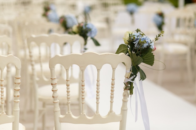 Bouquets of greenery and blue hydrangeas pinned to the white cha