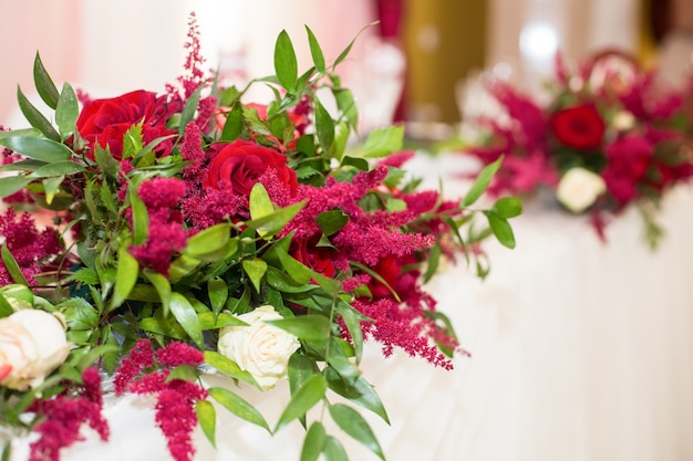 Bouquets of red flowers lie on white table in the restaurant 