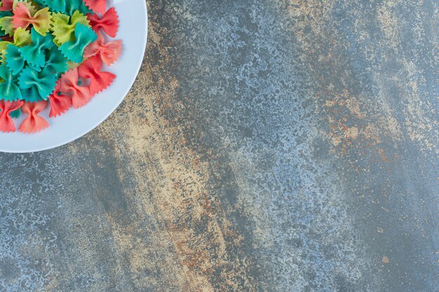 Bow tie pasta in the plate, on the tea tower , on the marble surface.