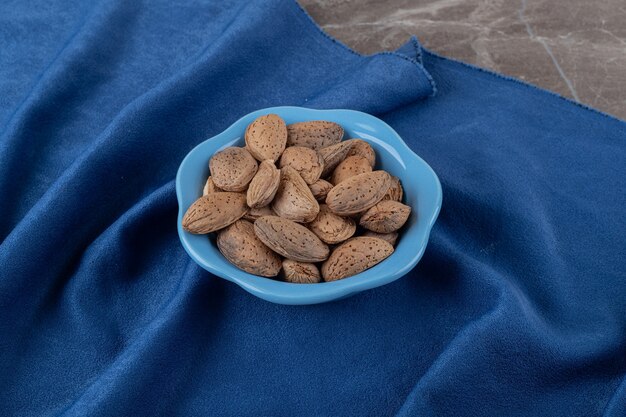 A bowl of almonds on the towel on the marble surface