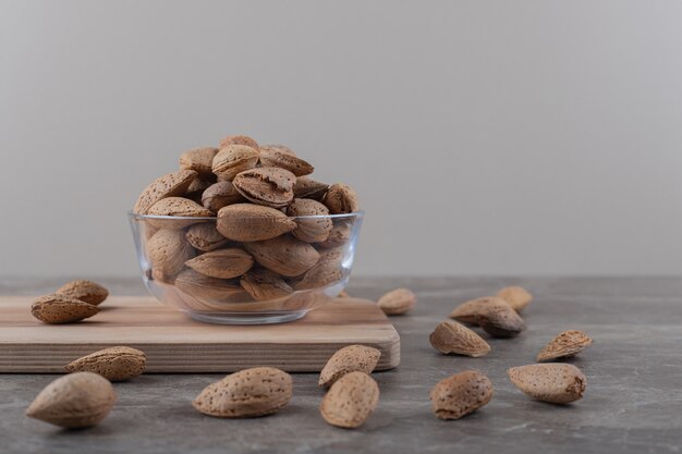 A bowl of almonds on a tray and scattered almonds on the marble surface