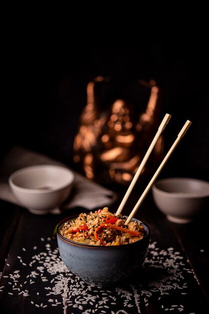 Bowl of asian food with rice and chopsticks