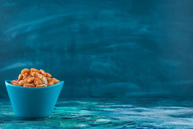 Bowl of baked beans, on the blue table. 