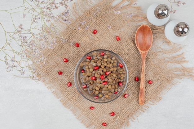 Free photo bowl of boiled beans with pomegranate seeds and salt on burlap.