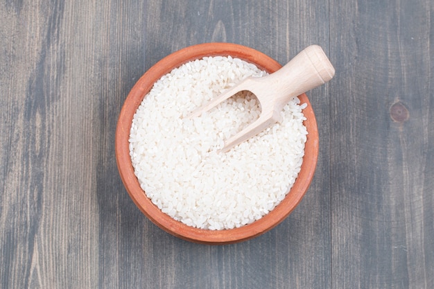 Bowl of boiled rice with spoon on wooden table