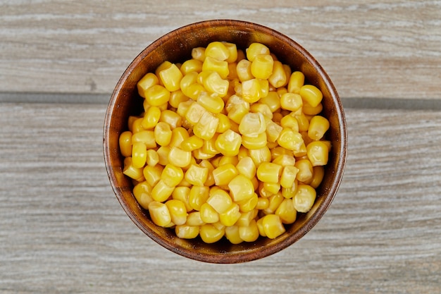 A bowl of boiled sweet corn on a wooden table.