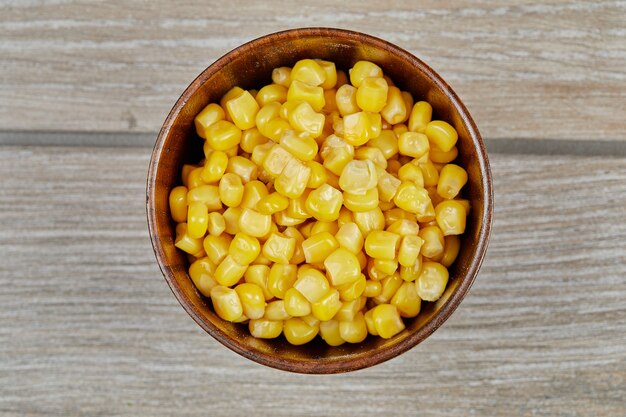 A bowl of boiled sweet corn on a wooden table.