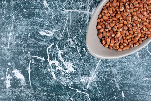 Bowl of brown beans on blue background. High quality photo