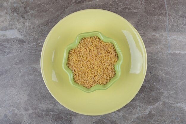 Free photo a bowl of bulgur on the plate ,on the marble surface
