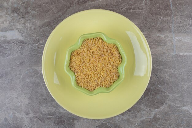 Foto gratuita una ciotola di bulgur sul piatto, sulla superficie del marmo