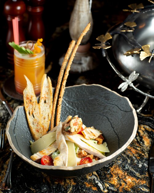 A bowl of caesar salad served with bread sticks