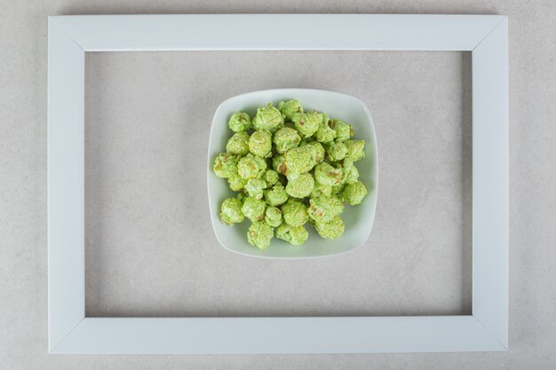 Free photo bowl of candied popcorn in the middle of an empty frame on marble.