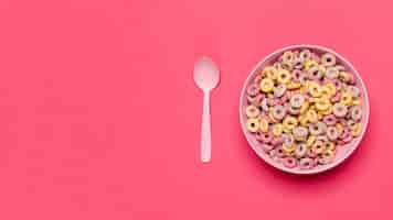 Foto gratuita ciotola di anelli di frutta cereali con cucchiaio