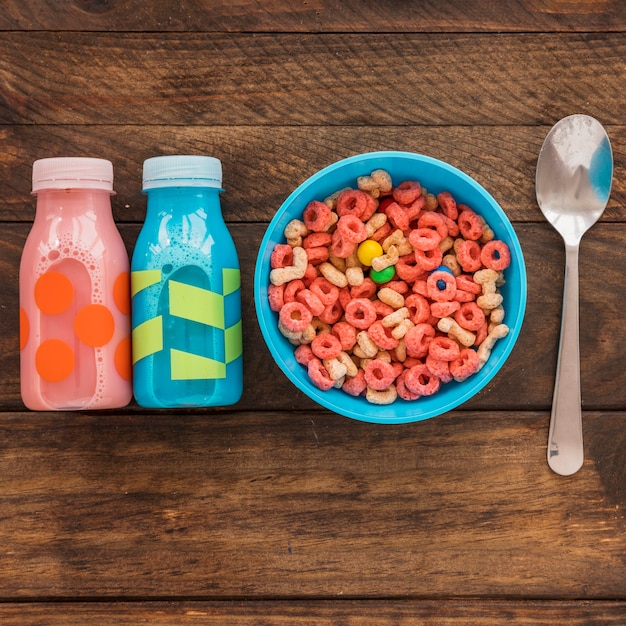 Bowl of cereal with two bottles and spoon