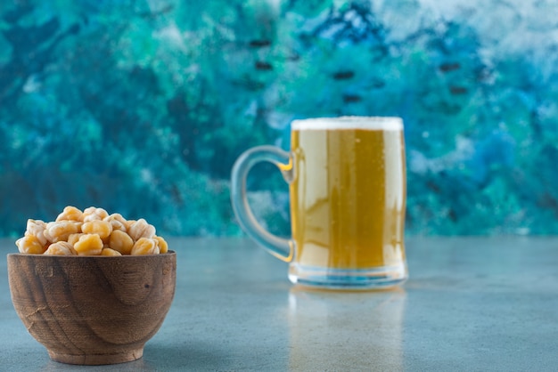 A bowl of chickpea and glass of beer , on the marble table. 