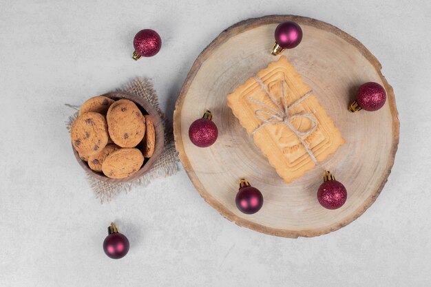 Bowl of chip cookies, biscuits and Christmas balls on white table. High quality photo