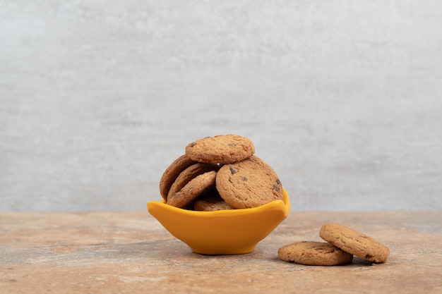 Bowl of chocolate chips cookies on marble background.