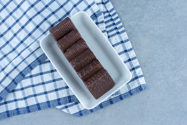 A bowl of chocolate coated on crispy wafer bar on the towel, on the marble table. 