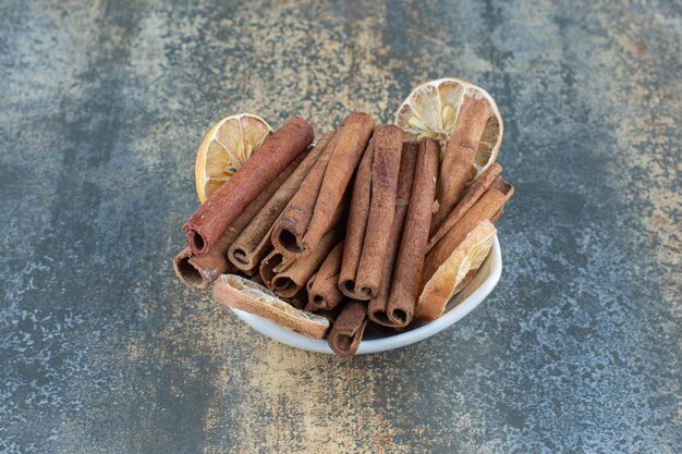 Bowl of cinnamon sticks on marble table.