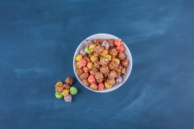Bowl of colorful cereal balls placed on a blue .
