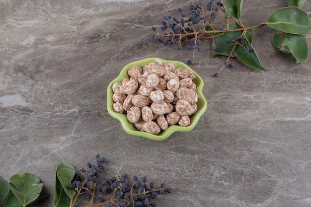 Free photo a bowl of confectionery with grape and leaves on the marble surface