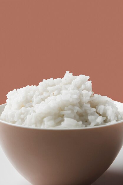 Bowl of cooked white rice against brown backdrop