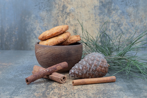 Bowl of cookies, pinecone and cinnamons on marble background. High quality photo