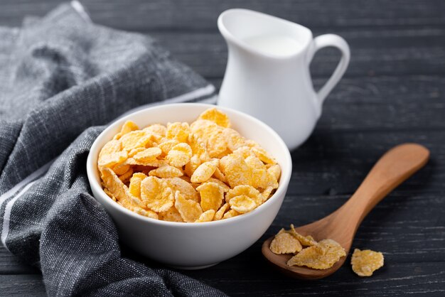 Bowl of corn flakes for breakfast with milk and wooden spoon