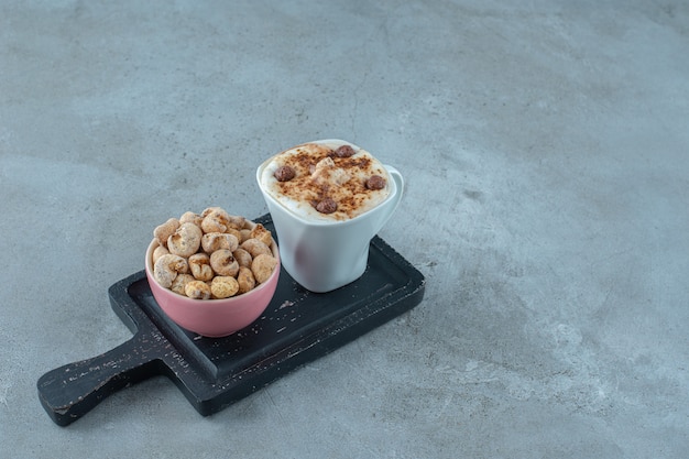 A bowl of cornflakes and a cup of cappuccino on a board , on the blue background. High quality photo
