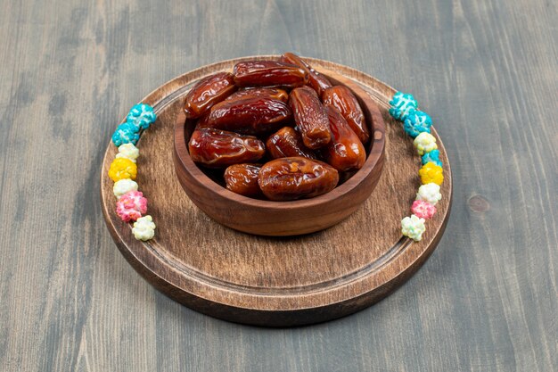 Bowl of dates and popcorns on wooden plate